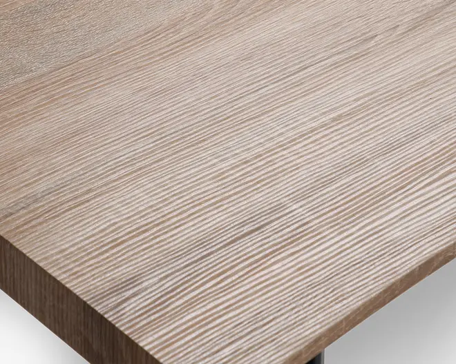 Nærbillede af en bordplade med lys egetræsstruktur. Overfladen har et tekstureret mønster af horisontale linjer i forskellige nuancer af beige og lysebrun, hvilket giver et naturligt og moderne udtryk. Kanterne er lige og rene, og finishen fremstår glat og mat.