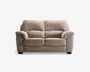 En to-personers sofa med blødt, lysebeige stofbetræk. Sofaen har fyldige, polstrede ryghynder og brede, polstrede armlæn for ekstra komfort. Sædehynderne er tykke og let buede foran, hvilket giver ergonomisk støtte. Sofaen står på korte, solide sorte ben.