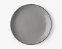 En rund, flad tallerken med en glat, blank overflade i en ensfarvet grå nuance. Tallerkenen har et minimalistisk design med en let hævet kant og et diskret, moderne udtryk. Kanterne er tynde, og finishen er jævn, hvilket giver et stilrent og nutidigt udseende.