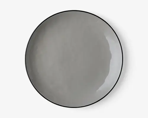 En rund, flad tallerken med en glat, blank overflade i en ensfarvet grå nuance. Tallerkenen har et minimalistisk design med en let hævet kant og et diskret, moderne udtryk. Kanterne er tynde, og finishen er jævn, hvilket giver et stilrent og nutidigt udseende.