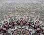 Nærbillede af et traditionelt mønstret tæppe med indviklede blomster- og geometriske motiver. Designet indeholder nuancer af grøn, creme, bordeaux og beige med detaljerede konturer i mørkegrå. Teksturen ser blød og fyldig ud, og mønsteret er symmetrisk, hvilket giver tæppet et klassisk og elegant udtryk.