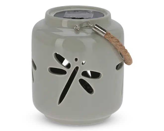 Rund, lysegrå lanterne i keramik med udskåret motiv af en guldsmed på siden. Øverst sidder et solpanel, og der er et kort rebhåndtag fastgjort med metalbeslag, så lanternen nemt kan bæres eller hænges op.