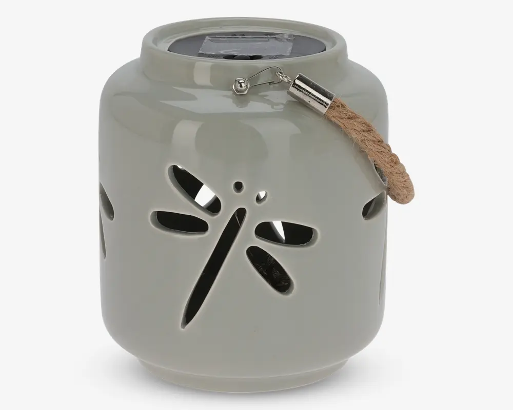 Rund, lysegrå lanterne i keramik med udskåret motiv af en guldsmed på siden. Øverst sidder et solpanel, og der er et kort rebhåndtag fastgjort med metalbeslag, så lanternen nemt kan bæres eller hænges op.