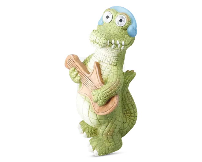 En finurlig figur formet som en grøn krokodille med teksturerede skæl, store rullende øjne og blå hovedtelefoner. Krokodillen står oprejst og holder en lysebrun guitar, hvilket giver den et legende og musikalsk udtryk. Detaljerne inkluderer en hvid bug, fremtrædende tænder og et venligt ansigtsudtryk.