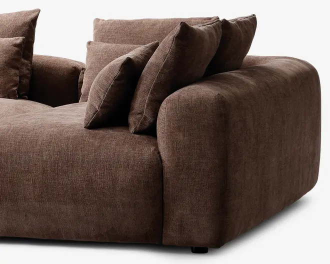 Blød, dyb siddeplads betrukket med et blødt, tekstureret brunt stof. Har brede, afrundede armlæn og ryglæn for ekstra komfort. Inkluderer flere store, matchende ryg- og sidepuder for ekstra støtte og et hyggeligt udseende. Det overordnede design er moderne med fokus på komfort og afslapning.