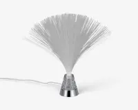 Dekorativ lampe med en vifteformet samling af fine, gennemsigtige fiberoptiske tråde, der spreder sig ud fra en central base. Basen er i metallisk sølv med en klar sektion fyldt med glimmer, og lampen har en synlig ledning til strøm. Fibrene lyser op, når lampen tændes, og skaber en glitrende, lysdiffuserende effekt.