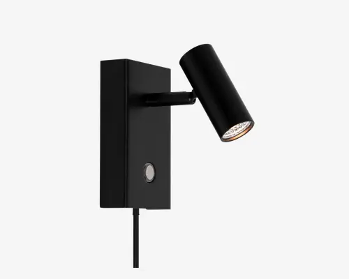 Elegant, moderne vægmonteret lampe med mat sort finish. Lampen har et cylindrisk, justerbart spotlys, der er fastgjort til en rektangulær base. Basen har en rund trykknap for nem betjening samt en synlig ledning, der går ud fra bunden. Minimalistisk design, der passer til nutidige indretninger.