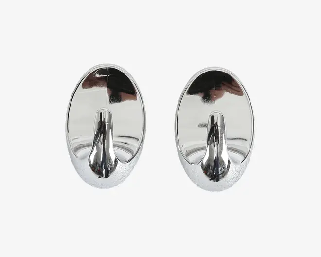Sæt med to ovale vægkroge med blank kromfinish. Hver krog har en glat, reflekterende overflade og en solid, buet krog, der stikker ud fra den nederste midte, velegnet til ophæng af f.eks. håndklæder, nøgler eller små tasker. Bagsiden er flad for nem montering på væggen.