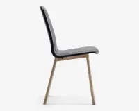 Sidevisning af en moderne stol med et slankt, buet sæde og ryglæn betrukket med sort materiale. Stolen har fire skråtstillede ben i lyst træ, hvilket giver et minimalistisk og stilfuldt udtryk. Sædet og ryglænet er glat formet for komfort.