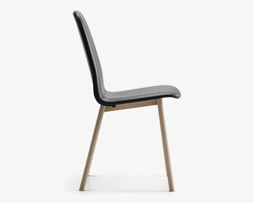 Sidevisning af en moderne stol med et slankt, buet sæde og ryglæn betrukket med sort materiale. Stolen har fire skråtstillede ben i lyst træ, hvilket giver et minimalistisk og stilfuldt udtryk. Sædet og ryglænet er glat formet for komfort.