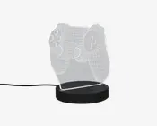 En dekorativ LED-lampe med en klar akrylplade, der er indgraveret med et 3D wireframe-design af en videospil-controller. Pladen er monteret på en rund, sort base, som indeholder LED-lyskilden. Lampen får strøm via et synligt USB-kabel, hvilket gør den velegnet til skriveborde eller natborde. De indgraverede linjer lyser op, når lampen er tændt, og fremhæver detaljerne i controller-designet.