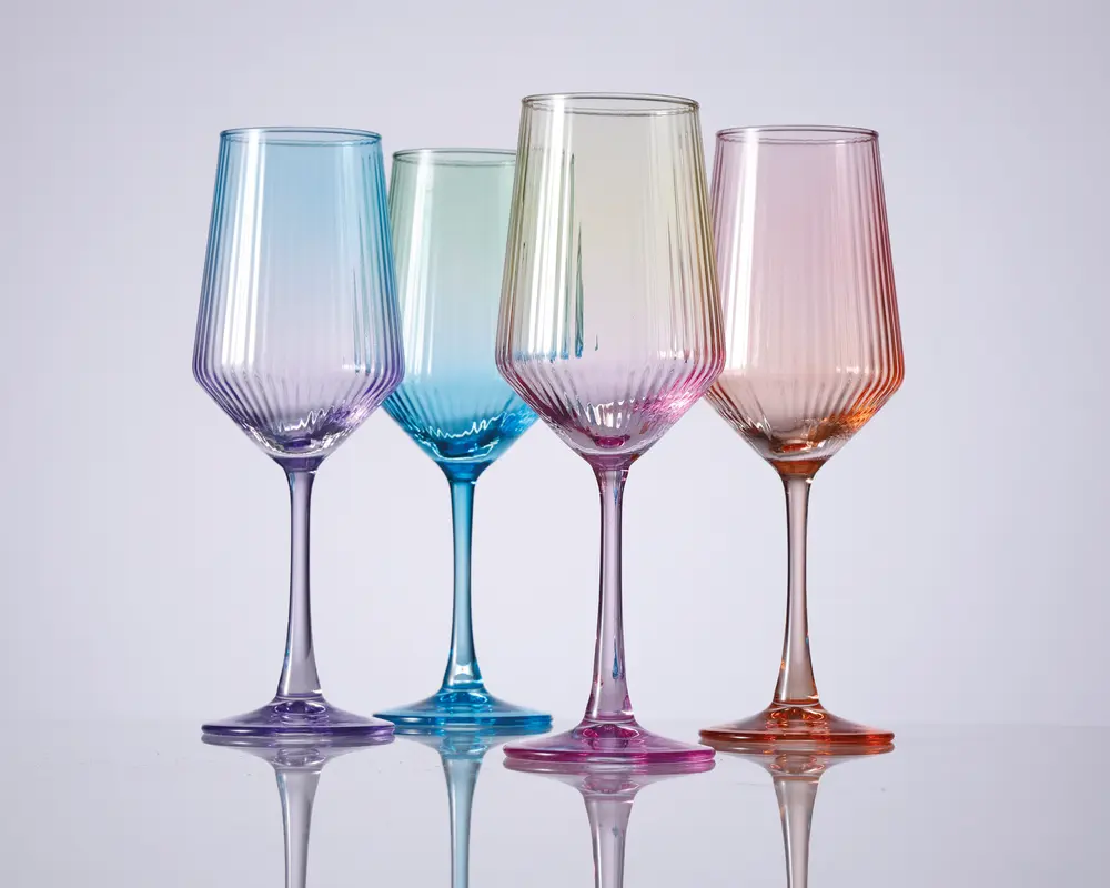Sæt med fire vinglas, hver med en forskellig pastelfarvet tone: blå, grøn, pink og orange. Glassene har et moderne design med lodrette riller på skålen og slanke stilke. Glasset er let gennemsigtigt, hvilket får farverne til at blande sig blødt. Hvert glas har en bred skål og en stabil fod, velegnet til servering af vin eller andre drikkevarer.