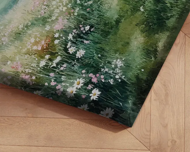 Nærbillede af et lærredsprint med et detaljeret maleri af en blomstereng. Kunstværket viser frodigt grønt græs med hvide og lyserøde blomster, herunder margueritter, og bløde, sammenblandede penselstrøg, der giver et naturligt og roligt udtryk. Lærredet er spændt over en træramme, og motivet fortsætter rundt om kanterne for et færdigt udseende.