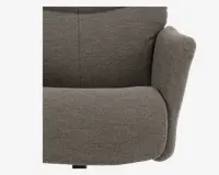 Nærbillede af en stol med blødt, tekstureret stof i en neutral brungrå farve. Sædet og ryglænet er tykt polstret for ekstra komfort, og armlænene er brede og afrundede, hvilket giver god støtte. Syningerne er diskrete og pæne, hvilket bidrager til et moderne og hyggeligt udtryk.