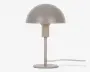 En moderne bordlampe med en mat, kuppelformet skærm i en blød beige farve. Lampen har en slank, cylindrisk stang og en rund, flad fod, begge i en matchende neutral tone. Strømkablet er synligt og går ud fra lampens fod. Designet er minimalistisk og nutidigt, velegnet til forskellige indretningsstile.