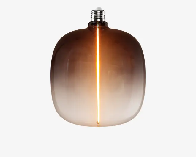 Pære med ravfarvet glas, afrundet rektangulær form, synlig lodret lysende glødetråd og sølvfarvet skruefatning.