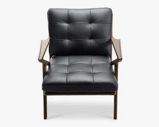 Stol med polstret sæde og ryglæn betrukket med sort læder og synlige firkantede syninger. Stellet og armlænene er lavet af lyst træ, hvilket giver en solid konstruktion og en moderne, stilfuld kontrast til det mørke betræk. Stolen har et bredt sæde og skrå armlæn for ekstra komfort.