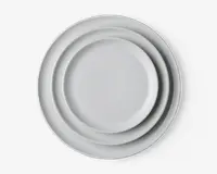 Sæt med tre runde tallerkener i forskellige størrelser, alle med en glat, ensfarvet hvid overflade og let hævet kant. Designet er minimalistisk og moderne, velegnet til forskellige borddækninger.