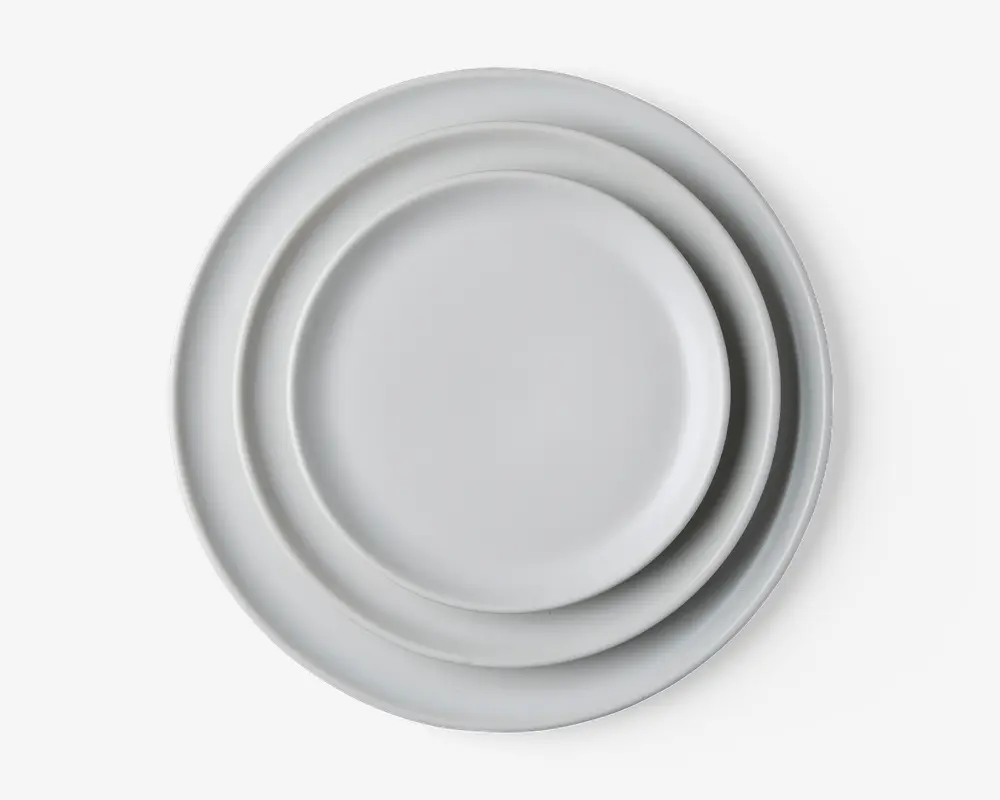 Sæt med tre runde tallerkener i forskellige størrelser, alle med en glat, ensfarvet hvid overflade og let hævet kant. Designet er minimalistisk og moderne, velegnet til forskellige borddækninger.