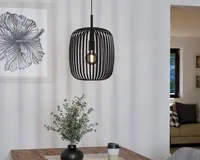 Et moderne pendellampe med en sort metalskærm i bur-stil, der har jævnt fordelte lodrette stænger. Pæren er synlig inde i skærmen og giver et varmt lys. Lampen hænger fra en sort ledning, og det minimalistiske design giver rummet et moderne udtryk.