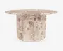 Rundt bord med en kraftig, solid stentop og en robust, geometrisk piedestalbase. Overfladen og basen har et naturligt, plettet beige og taupe stenmønster, der giver et tekstureret og jordnært udtryk. Bordpladens kanter er let affasede for et elegant finish.