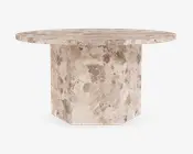 Rundt bord med en kraftig, solid stentop og en robust, geometrisk piedestalbase. Overfladen og basen har et naturligt, plettet beige og taupe stenmønster, der giver et tekstureret og jordnært udtryk. Bordpladens kanter er let affasede for et elegant finish.