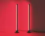 Et par slanke, lodrette LED-lysstænger med sorte baser, der udsender et kraftigt rødt skær. Lysene står side om side, hver med en strømledning, der går ud fra basen. Designet er minimalistisk og moderne, velegnet som accent- eller stemningsbelysning i nutidige indretninger.