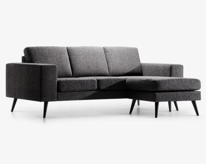 Moderne hjørnesofa betrukket med mørkegråt stof og højrevendt chaiselong. Sofaen har rene linjer, tre ryghynder og slanke, koniske sorte ben, der giver et moderne udtryk. Armlænene er lige og polstrede for komfort, og sædehynderne fremstår faste og støttende.