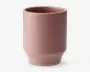En mat, støvet lyserød keramikkop med glat overflade og et minimalistisk cylindrisk design. Koppen har en let tilspidset bund og en bred åbning, uden synligt hank eller dekorative detaljer.