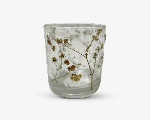 Klar glas tumbler med indlejrede tørrede blomster og fine stilke, hvilket giver et naturligt og dekorativt udseende. Overfladen har en let tekstureret finish, og blomsterne er arrangeret, så de kan ses fra alle sider, hvilket giver et unikt, håndlavet præg.