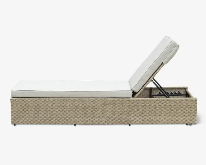 Rektangulær udendørs liggestol med en flettet rattanbase i lys beige farve. Stolen har en tyk, lysefarvet hynde for komfort og et justerbart ryglæn, der kan hæves eller sænkes til forskellige vinkler. Designet er moderne og minimalistisk, velegnet til terrasse eller poolområde.