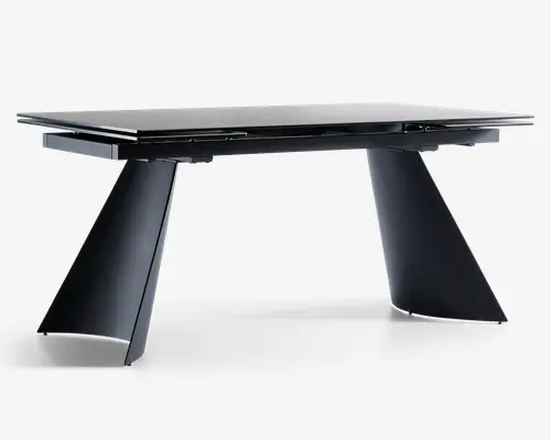 Moderne bord med en blank, sort rektangulær bordplade med skarpe kanter. Bordet understøttes af to brede, vinklede ben, der skråner udad og giver et nutidigt og geometrisk udtryk. Designet er minimalistisk uden synlige beslag eller udsmykning, hvilket fremhæver de rene linjer og den solide konstruktion.