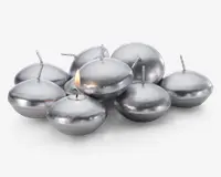 En gruppe runde, sølvfarvede flydelys med en glat, metallisk overflade. Hvert lys har en kort væge i midten, og ét af lysene er tændt med en lille flamme. Lysene har en let fladtrykt, skiveformet facon, der egner sig til at flyde på vand.