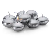 En gruppe runde, sølvfarvede flydelys med en glat, metallisk overflade. Hvert lys har en kort væge i midten, og ét af lysene er tændt med en lille flamme. Lysene har en let fladtrykt, skiveformet facon, der egner sig til at flyde på vand.