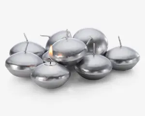 En gruppe runde, sølvfarvede flydelys med en glat, metallisk overflade. Hvert lys har en kort væge i midten, og ét af lysene er tændt med en lille flamme. Lysene har en let fladtrykt, skiveformet facon, der egner sig til at flyde på vand.