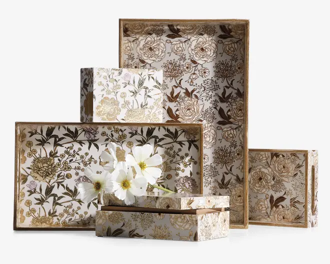 Sæt af dekorative rektangulære og firkantede æsker i forskellige størrelser med et detaljeret blomstermønster i nuancer af guld, brun og creme. Æskerne har et vintage-inspireret design med fine blomster og blade samt en diskret metallisk glans. Kanterne er indrammet med en guldfarvet kant, der giver et elegant udtryk. En af æskerne er åben og indeholder hvide blomster, hvilket viser en mulig anvendelse til dekoration eller opbevaring.