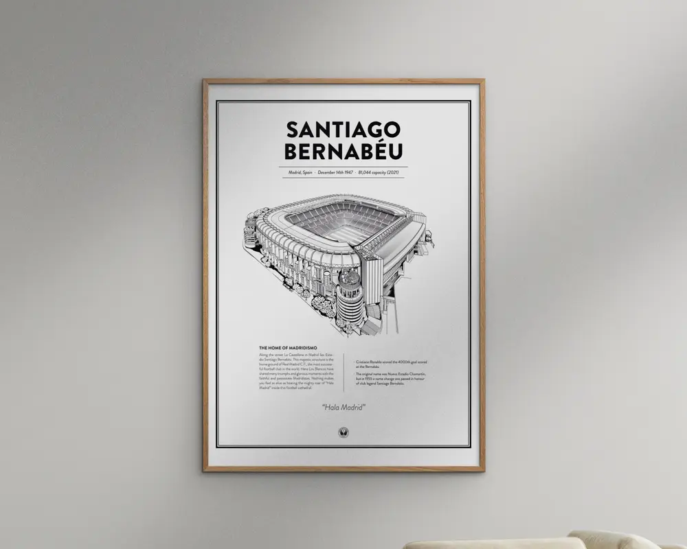 En indrammet plakat med en detaljeret sort-hvid arkitektonisk illustration af Santiago Bernabéu-stadionet. Plakaten har fed tekst øverst med stadionets navn, efterfulgt af mindre tekst med information om placering, åbningsdato og kapacitet. Under illustrationen er der et afsnit med beskrivende tekst om stadionet samt et citat. Rammen er enkel og i lyst træ, og plakaten har et rent, minimalistisk design med hvid baggrund og en tynd sort kant.