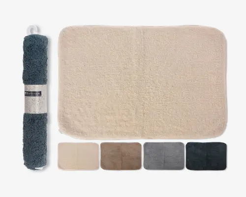 Rektangulært bademåtte med blød, plysset overflade og afrundede hjørner. Billedet viser måtten i en lys beige farve, med yderligere farvemuligheder vist nedenfor: beige, brun, lysegrå, mørkegrå og mørkeblå. Måtten vises også sammenrullet med et mærkat, hvilket indikerer, at den er nem at opbevare eller transportere. Overfladen ser tyk og absorberende ud, velegnet til badeværelset.