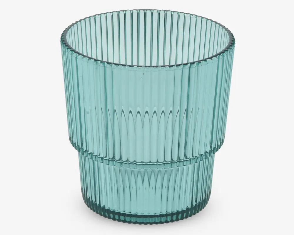 Et transparent, lyseblåt drikkeglas med lodret rillet tekstur. Glasset har en cylindrisk form og en markant vandret kant omkring midten, som deler det rillede mønster i to sektioner. Designet giver glasset et moderne og stilfuldt udtryk.