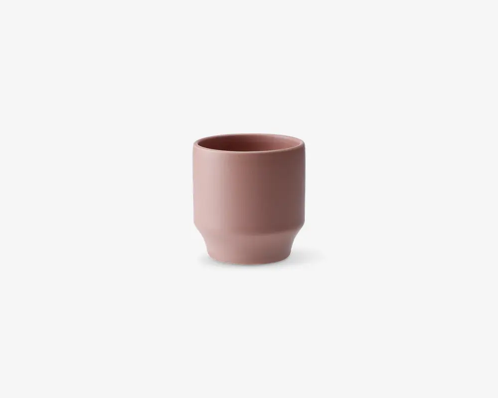 En lille, cylindrisk kop med mat rosa finish. Koppen har en glat overflade, let tilspidset bund og lige kant. Det minimalistiske design giver et moderne og elegant udtryk.