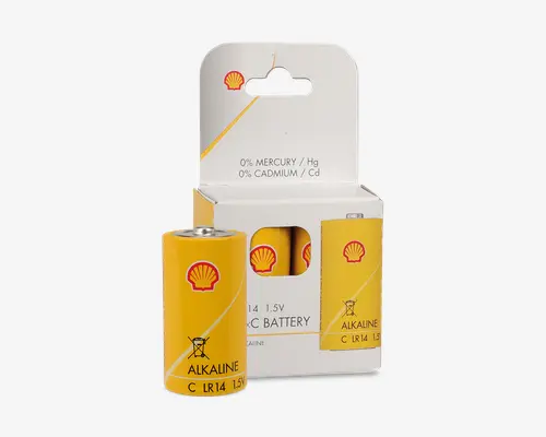 Gul cylinderformet batteri med rødt Shell-logo, mærket som alkalisk type C LR14 med 1,5V. Emballagen er hvid med gule detaljer og har et udskåret vindue, der viser batteriet indeni. Pakken fremhæver, at batteriet indeholder 0 % kviksølv og 0 % cadmium. Batteriet har tydelig mærkning af type og spænding, og emballagen har en ophængningsfane til udstilling.