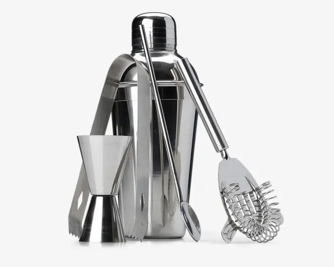 Et sæt barværktøj i rustfrit stål, der inkluderer en cocktailshaker med tætsluttende låg, en dobbeltsidet målebæger til væsker, en lang røreske, en fjeder cocktail-si og et par istænger. Alle dele har en blank, poleret overflade og er designet til holdbarhed og nem rengøring.