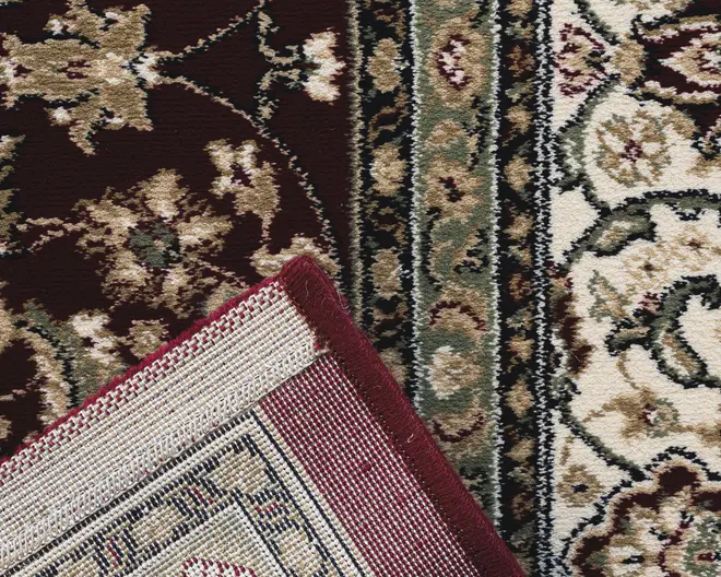 Nærbillede af et traditionelt mønstret tæppe med indviklede blomster- og vinmønstre i nuancer af bordeaux, creme, olivengrøn og beige. Tæppet har en detaljeret kant med gentagne blomstermotiver og en tæt vævet bagside for holdbarhed. Kanten er afsluttet med en bordeaux kant for at forhindre, at det frynser.