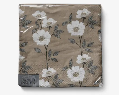 Beige serviet med trykt blomstermønster, der viser hvide blomster med gule midter og grønne blade. Blomsterne er arrangeret på lange, slanke stilke, hvilket giver et naturligt og elegant udtryk. Servietten har en diskret tekstureret kant og et lille mærke i hjørnet med teksten 'Danish Design.' Det overordnede udtryk er moderne og egner sig til både uformelle og formelle borddækninger.