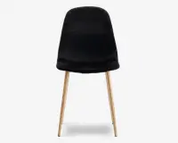 Stol med glat, sort polstret sæde og ryglæn, der har et let buet design for komfort. Stolen står på fire skråtstillede ben i lyst træ, hvilket giver en moderne kontrast til det mørke sæde. Stilen er minimalistisk og moderne.
