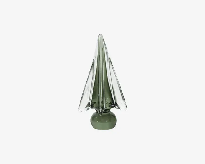 Dekorativt objekt lavet af glas, formet som et stiliseret træ med spids top og kantede, facetterede sider. Glasset har en grønlig tone, hvilket giver det et gennemsigtigt udseende, og det står på en rund fod. Overfladen er glat og reflekterende, hvilket giver et moderne og elegant udtryk.