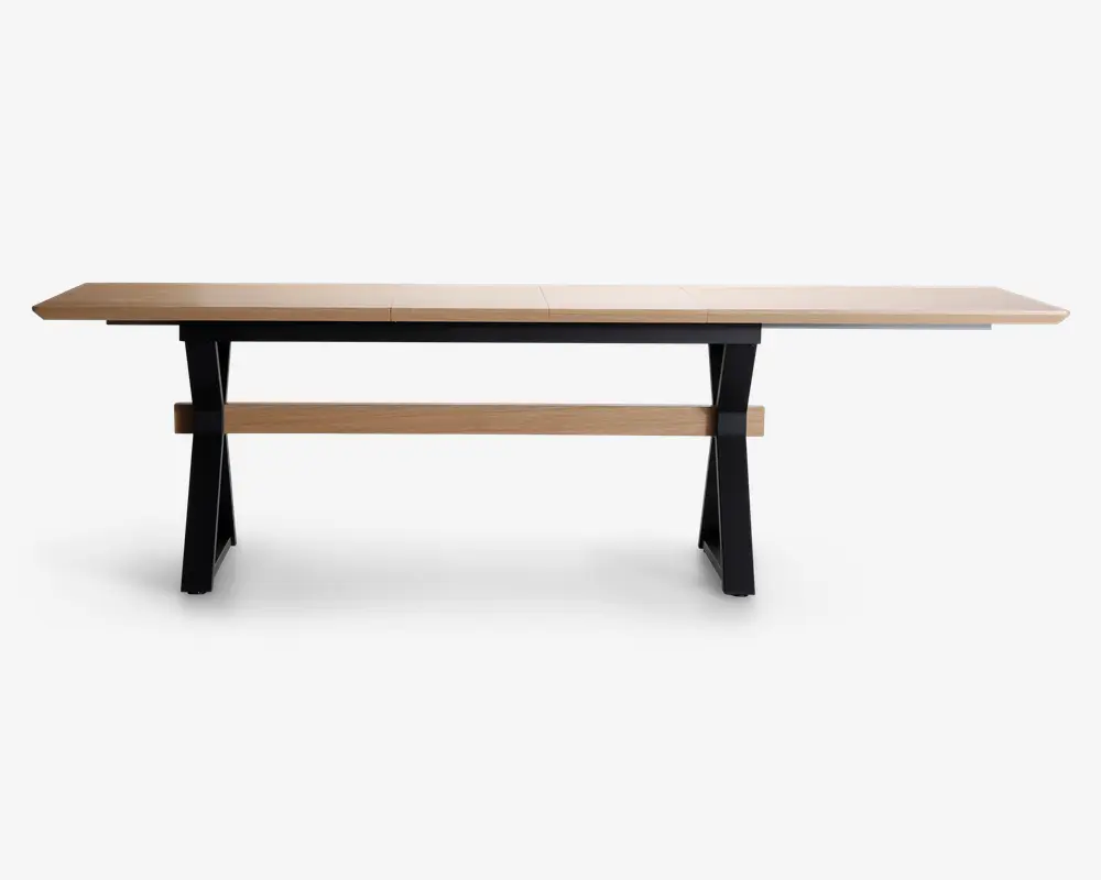 Et langt, rektangulært bord med en lys træbordplade og solide sorte metalben. Bordet har et minimalistisk design med rene linjer og en vandret træstøtte, der forbinder benene for ekstra stabilitet. Overfladen er glat og rummelig, velegnet til at rumme flere personer.