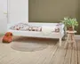 En minimalistisk, lav sengestel med en enkel, hvid finish. Stellet har rene, lige linjer og både hoved- og fodende er lige høje, hvilket giver et moderne og alsidigt udtryk. Sengen er vist med en dyne med geometrisk mønster i jordfarver og et blødt, hvidt kunstpels-tæppe. Stellet står direkte på gulvet uden synlig opbevaring under sengen, hvilket gør det velegnet til små rum eller børneværelser. Den solide konstruktion og neutrale farve gør det nemt at matche med forskellige indretninger.