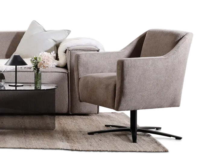 Moderne lænestol med blødt, tekstureret lysebrunt stofbetræk. Stolen har en buet ryg og armlæn for ekstra komfort samt en tyk, polstret siddehynde. Den står på en sort, firebenet metalfod med drejefunktion, som giver stabilitet og nem bevægelse. Designet er moderne og passer godt til stue eller kontor.