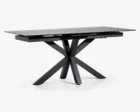 Rektangulært bord med en elegant, mat sort finish. Bordpladen er flad og glat, understøttet af en markant geometrisk base med fire skråtstillede ben, der mødes i midten og giver et moderne, skulpturelt udtryk. Bordet fremstår robust og rummeligt, velegnet til spise- eller arbejdsbrug.